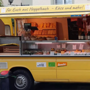 Besucher schlendern über den Konstanzer Bio-Markt auf der Konzil-Mole: Stände mit Käse, Brotaufstrichen, Gemüse und Wein von regionalen Erzeugern, darunter die Hofkäserei Heggelbach und Delikat essen.